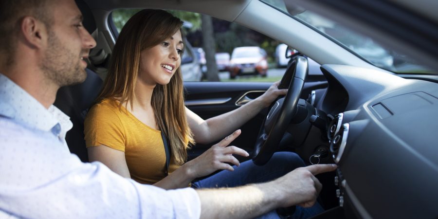 driving instructor showing vehicle dashboard and buttons to the student taking driving lessons.